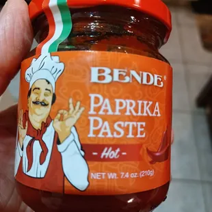 a hand holding a jar of hot sauce