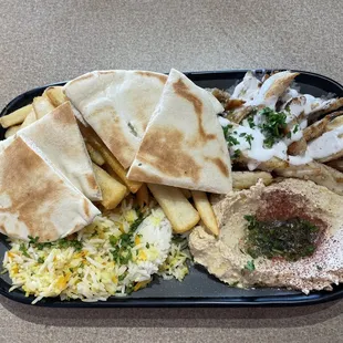 Chicken shawarma plate with rice, hummus, and fries.