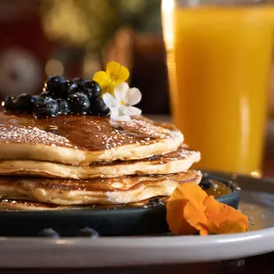 a stack of pancakes with syrup and blueberries