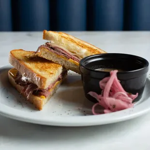 Short Rib Grilled Cheese - braised short rib with American, provolone, and sourdough. Served with au jus and pickled red onion.
