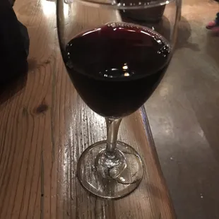 a glass of red wine on a wooden table