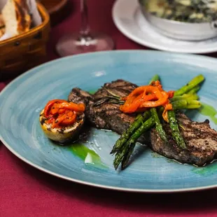New York Steak: A succulent 12oz striploin grilled to perfection, paired with creamed spinach, truffle oil, and asparagus.