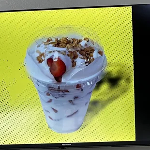 a glass of milkshake with strawberries and granola