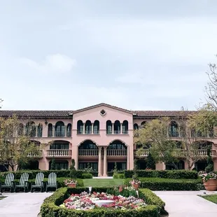 a pink building with a circular garden in front of it