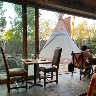 a woman sitting at a table in front of a teepee