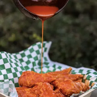 auce being poured over chicken wings