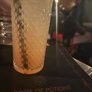 a glass of lemonade on a book of potions