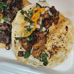 two tacos and beans in a styrofoam container