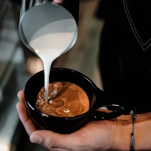 a person pouring milk into a cup