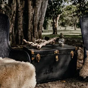 Wedding Lounge. Wedding Rentals. Black Wicker High-back Chairs. Vintage Antique Black Trunk. Lantern. Beach Wood.