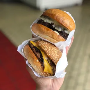 a hand holding three hamburgers