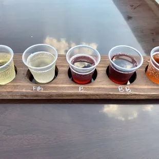 a flight of beers on a wooden tray