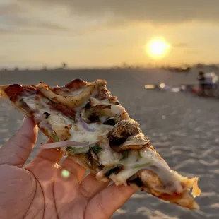 a hand holding a slice of pizza