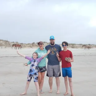 Our family posing on Cumberland Island Beach with wild horses passing in the background.