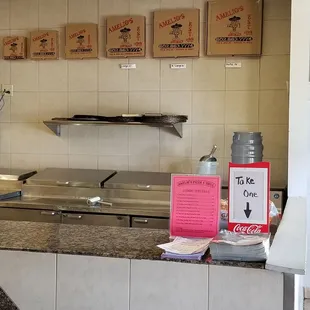 a kitchen counter with pizza boxes on the wall