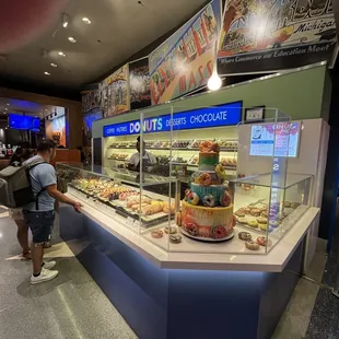 a man standing in front of a display of donuts