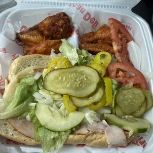 a sandwich with meat, lettuce, and pickles