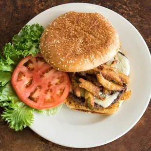 a hamburger with lettuce, tomato, and onion rings
