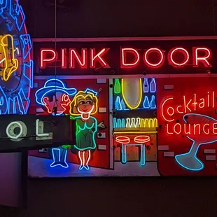 a neon sign for a pink door cocktail lounge