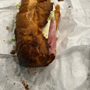 a half eaten sandwich on a piece of wax paper
