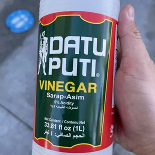 a hand holding a bottle of vinegar