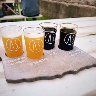 four different beers on a slate board