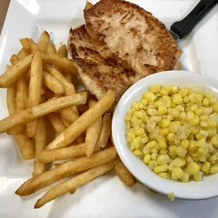Boneless pork chops with corn and french fries.