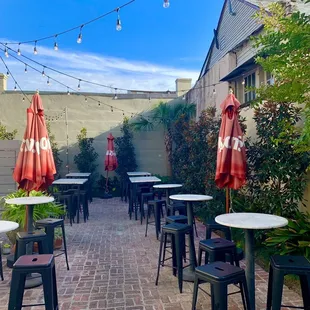 a brick patio with tables and umbrellas
