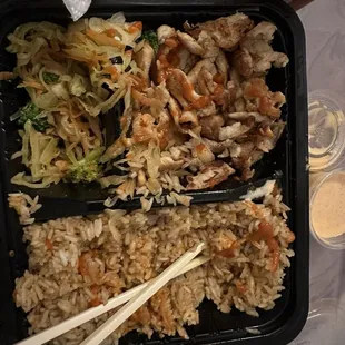 a meal in a plastic container with chopsticks