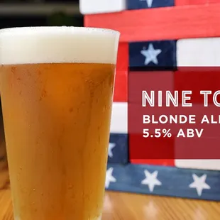 a pint of beer in front of a stack of books