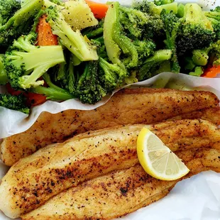 a plate of fish, broccoli, and carrots