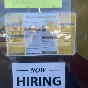 a now hiring sign in a window
