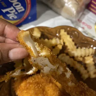 a hand holding a piece of fried chicken