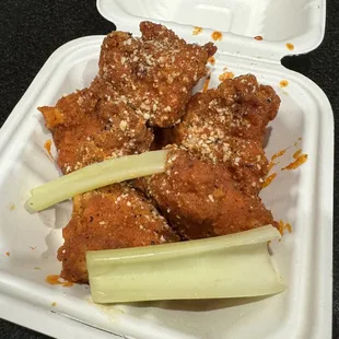 chicken wings and celery sticks in a styrofoam container
