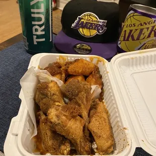 a tray of chicken wings and a can of beer
