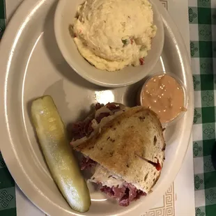 a plate with a sandwich, mashed potatoes, and a pickle