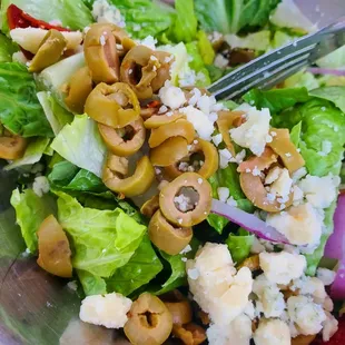 a salad with lettuce, olives, and feta cheese