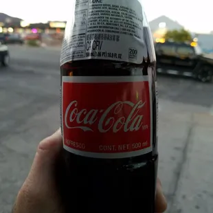 a hand holding a bottle of coca cola