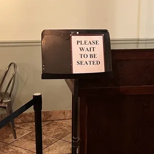 a sign that reads please wait to be seated