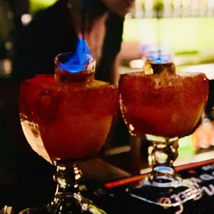 two glasses of cocktail on a bar