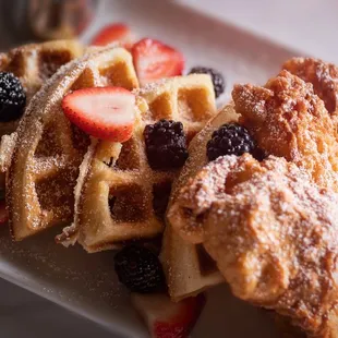 a plate of waffles with berries and powdered sugar