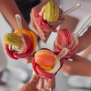a group of people holding up macarons