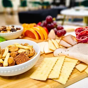 a cheese board with crackers, crackers, grapes, and fruit
