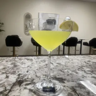 a glass of yellow liquid with a slice of lemon