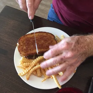 a person cutting a sandwich with a knife