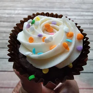a hand holding a cupcake