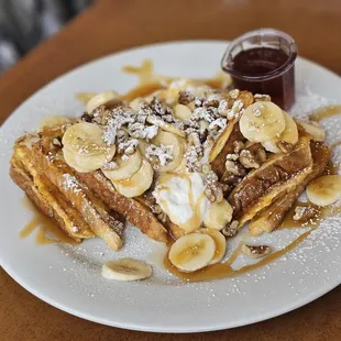 a plate of french toast topped with bananas and whipped cream