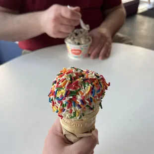 a hand holding an ice cream cone with sprinkles