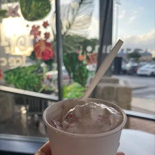 a hand holding a cup of ice cream