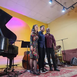 a group of people standing in front of a piano